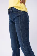 Pantalón de jean azul oscuro, corte semi Oxford, con costuras verticales en el frente.