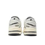 Championes New Balance modelo 1000 de hombre, color crema con detalles en gris y logo "N" en los laterales.