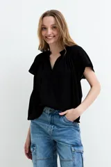 Blusa de manga corta color negro, con escote en V y frunces en los hombros, de diseño holgado y ligero.