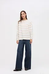 Remera de manga larga con diseño a rayas horizontales en color crema y rojo. Presenta un corte holgado, cuello redondo y un pequeño bordado en el pecho.