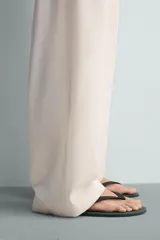 Sandalia tipo ojota o chancleta de goma, con base de color verde oscuro y tiras negras. Presenta una suela plana.