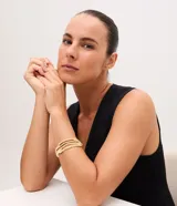 Pulsera rígida de diseño abierto con textura grabada y acabado en tono dorado. Presenta un estilo moderno y minimalista, ideal para complementar diversos looks.