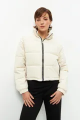 Campera puffer corta color beige de nylon, con cuello alto, cierre frontal y bolsillos laterales con cierre.