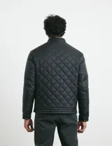 Campera capitoneada de color azul oscuro, con cierre frontal de metal y botones a presión. Presenta bolsillos laterales y en el pecho con cierres metálicos.