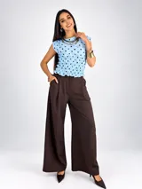 Blusa sin mangas de viscosa color negro con estampado de lunares blancos, cuello redondo y cintura fruncida con elástico.