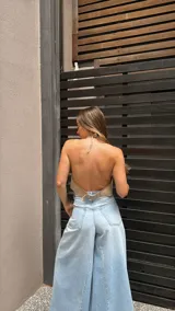 Top halter color beige, estilo chaleco corto, con cuello alto y bordes festoneados con costura decorativa.