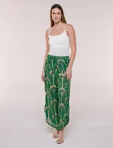 Pantalón palazzo verde de gasa con sutil transparencia y estampa metalizada dorada. Presenta cintura elastizada con cordón ajustable terminado en borlas y diseño de piernas anchas cruzadas en el frente con terminación de puntilla en los bordes.