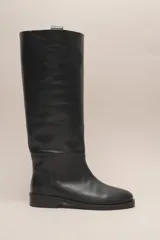 Bota de caña alta color marrón, confeccionada en cuero vacuno con forro y plantilla de cuero. Tiene suela de goma negra y un diseño de caña ancha.