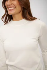 Polera de manga larga color blanco hueso, con cuello simulado (mock neck) y tejido de punto fino.