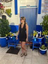 Vestido corto negro con escote halter y cierre frontal con cremallera dorada.