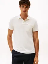 Chomba de manga corta en tejido jacquard elástico color blanco con textura de rayas horizontales. Presenta cuello clásico, tapeta con dos botones y un bolsillo de parche en el pecho con cierre de cremallera y logo bordado.