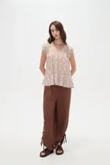 Blusa de poliéster sin mangas con cuello redondo y estampado geométrico en tonos marrones y blancos, de corte holgado y diseño fluido.
