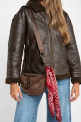 Campera tipo gamulán de corte oversize, color marrón oscuro con efecto cuero envejecido. Presenta cuello solapa, puños y ruedo con forro de corderito sintético en tono marrón oscuro. Cuenta con cierre frontal completo y detalles de costuras reforzadas.