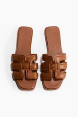Sandalias planas de color marrón, con punta cuadrada y tiras superiores entrelazadas y levemente acolchadas.