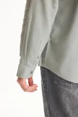 Camisa de lino de manga larga, color beige, con cuello clásico y cierre frontal de botones.