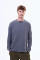 Buzo de manga larga con textura tipo waffle, cuello redondo y corte holgado.