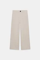 Pantalón de tiro alto color beige, con costuras marcadas en la parte delantera y cierre frontal de cremallera con botón negro a contraste.