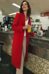 Abrigo largo de Zara confeccionado en mezcla de lana color rojo, con cuello de solapa, manga larga, bolsillos con solapa en el frente y cierre frontal de botones negros.