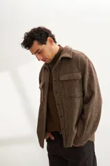 Camisa estilo leñadora marrón con diseño de espiga, cuello clásico, abrochadura frontal a la vista, bolsillos plaqué con tapa en el pecho, mangas largas con puño y botón.