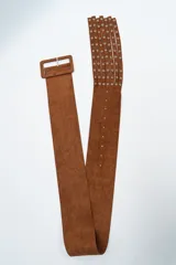 Cinturón ancho de gamuza color marrón, con hebilla rectangular forrada y extremo terminado en flecos con detalles de ojalillos metálicos.