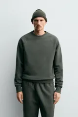 Sudadera de corte relajado confeccionada en algodón compacto con interior de rizo. Presenta cuello redondo, mangas largas tipo raglán y terminaciones en rib.