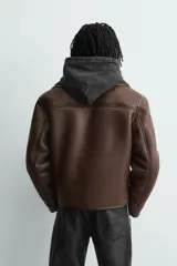 Cazadora cropped fit de tejido efecto piel en color marrón, con interior de borreguillo a tono. Presenta cuello solapa, cierre frontal con botones, bolsillos de plastrón en el pecho y bolsillos de vivo en la cadera.