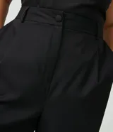 Pantalón de sastrería corte carrot, color negro, con cintura alta, pliegues delanteros, bolsillos laterales y elástico en la parte posterior de la cintura.