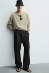 Pantalón de corte wide fit y largo cropped, confeccionado en tejido con elasticidad. Presenta cintura con pliegues frontales, bolsillos laterales y bolsillos traseros de vivo. Cierre frontal con cremallera y botón.