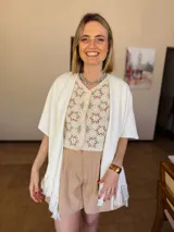 Ruana tejida de forma artesanal en color natural, con diseño de textura sutil y terminación de flecos en los bordes.