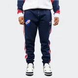 Pantalón de jogging azul marino de felpa, con franjas laterales en rojo y blanco. Presenta el escudo del Club Nacional de Football en el muslo derecho y el logo de Umbro en el izquierdo, con cintura elástica y cordón de ajuste.