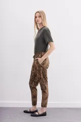 Pantalón babucha de tiro medio, ajustado en tobillos, con estampado de piel de serpiente en tonos marrones y negros. Posee bolsillos diagonales y cintura elastizada con cordón de ajuste.