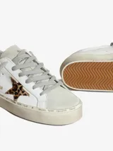 Zapatillas Golden Goose modelo Hi Star, color blanco con estrella plateada y detalles en animal print. Plataforma con texto estampado.