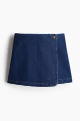 Short pollera cruzado de sarga de algodón color azul oscuro, con un botón decorativo visible en el lateral superior y cierre oculto frontal. Presenta bolsillos insertados decorativos en la parte trasera.