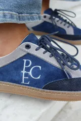 Championes de estilo urbano en combinación de tonos marrones y crema, confeccionados en gamuza y cuero. Presentan cordones jaspeados, suela de goma y detalle de logo bordado en el lateral.