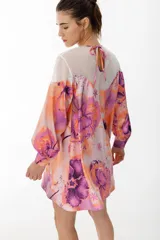 Vestido corto con vuelo de satén con maxi estampado floral combinado con organza semitransparente con líneas en el canesú. Tiene manga larga abullonada y lazo en la espalda para anudar.