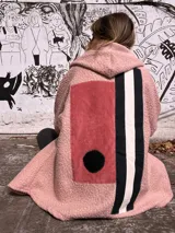 Campera tipo hoodie confeccionada en técnica de collage con texturas combinadas. Presenta cuerpo principal en tejido tipo corderito rosa, con paneles traseros en pana rosa, detalles en franjas verticales blancas y negras, y un aplique circular negro. Incluye capucha integrada.