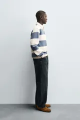 Sudadera de manga larga estilo polo con diseño de rayas horizontales anchas en azul marino y blanco. Presenta cuello de solapa en contraste, cierre frontal con botones ocultos y acabados en rib en puños y bajo.