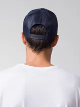 Gorra tipo trucker color azul marino con diseño de 5 paneles, visera curva y parte trasera de malla. Cuenta con un parche frontal con el logo de Caterpillar.