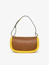 Bolso de hombro JW Anderson modelo Bumper-15, color marrón con ribetes tubulares acolchados amarillos. Tiene correa ajustable, cierre con cremallera superior y logo estampado en el frente.