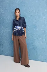 Camisa de calce relajado con cuello clásico, mangas largas con puños elastizados y rayas verticales que aportan un estilo atemporal. Su diseño liviano y versátil cuenta con estampado floral verde sobre fondo de rayas celestes y blancas.
