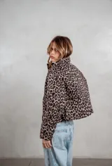 Campera puffer corta con estampado animal print, cuello alto y cierre frontal. Cuenta con bolsillos laterales y diseño acolchado.