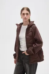 Campera con capucha de diseño híbrido, combinando un panel frontal acolchado con diseño ondulado y mangas de tejido liso. Cuenta con cierre frontal completo, puños elásticos y bolsillos laterales.