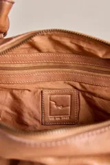 Cartera de cuero verde militar con acabado gastado, cuerpo blando, asas de mano, bolsillos frontales con cierre y tiras colgantes.