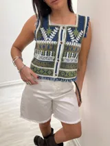 Chaleco corto en denim con bordado artesanal multicolor y escote cuadrado. Con cierre de botones y terminaciones desflecadas.