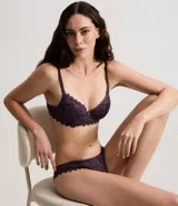 Bombacha modelo bikini confeccionada íntegramente en encaje floral color verde oliva, con detalle de pequeña medalla metálica en la parte frontal y forro de algodón.