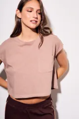 Remera gris de algodón con poliéster, corte crop, mangas cortas y bolsillo en el pecho.