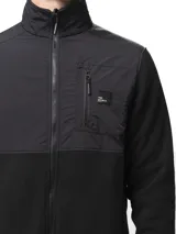 Campera de polar negro con paneles de nylon en el pecho, cuello alto, cierre frontal completo, bolsillo con cierre en el pecho y bolsillos laterales con cierre.