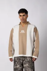Sweater de tejido de punto con diseño de rayas verticales en tonos beige y blanco. Presenta cuello polo abierto, mangas largas y un corte holgado. Incluye un logo bordado en el centro del pecho.