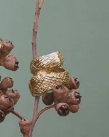 Anillo de diseño abierto con textura escamada que simula la piel de una serpiente, elaborado artesanalmente en metales nobles.