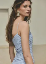 Vestido midi color celeste con diseño evasé, cuello asimétrico de un solo hombro con tirante fino, cuerpo fruncido y cierre de cremallera lateral.